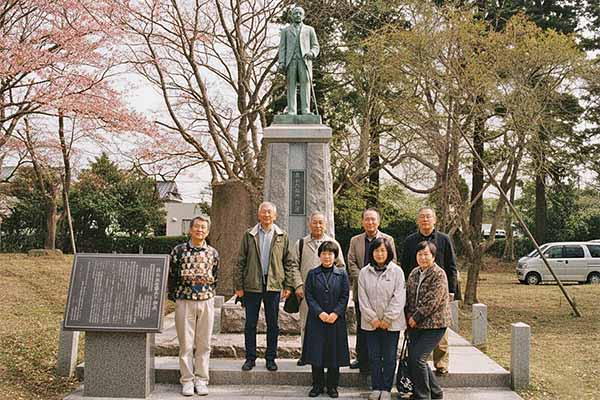 新山壮輔の銅像の前にて地元住人と親族